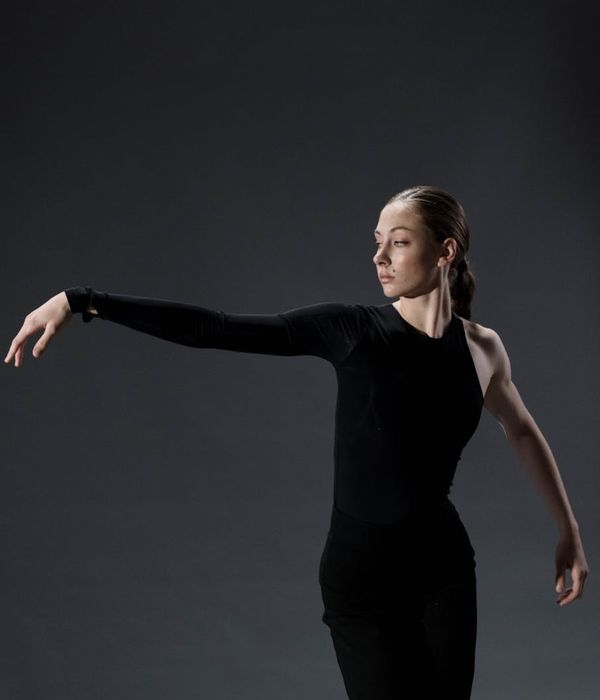 Woman in activewear performing a fluid cardio movement in a dark studio with blue light.